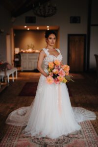 Bride in a white dress holding a flame coloured bouquet